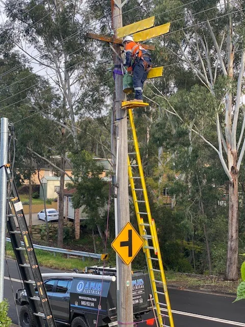 Ladder set against a power pole for overhead work